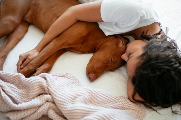 Woman and dog sleeping in a bed.